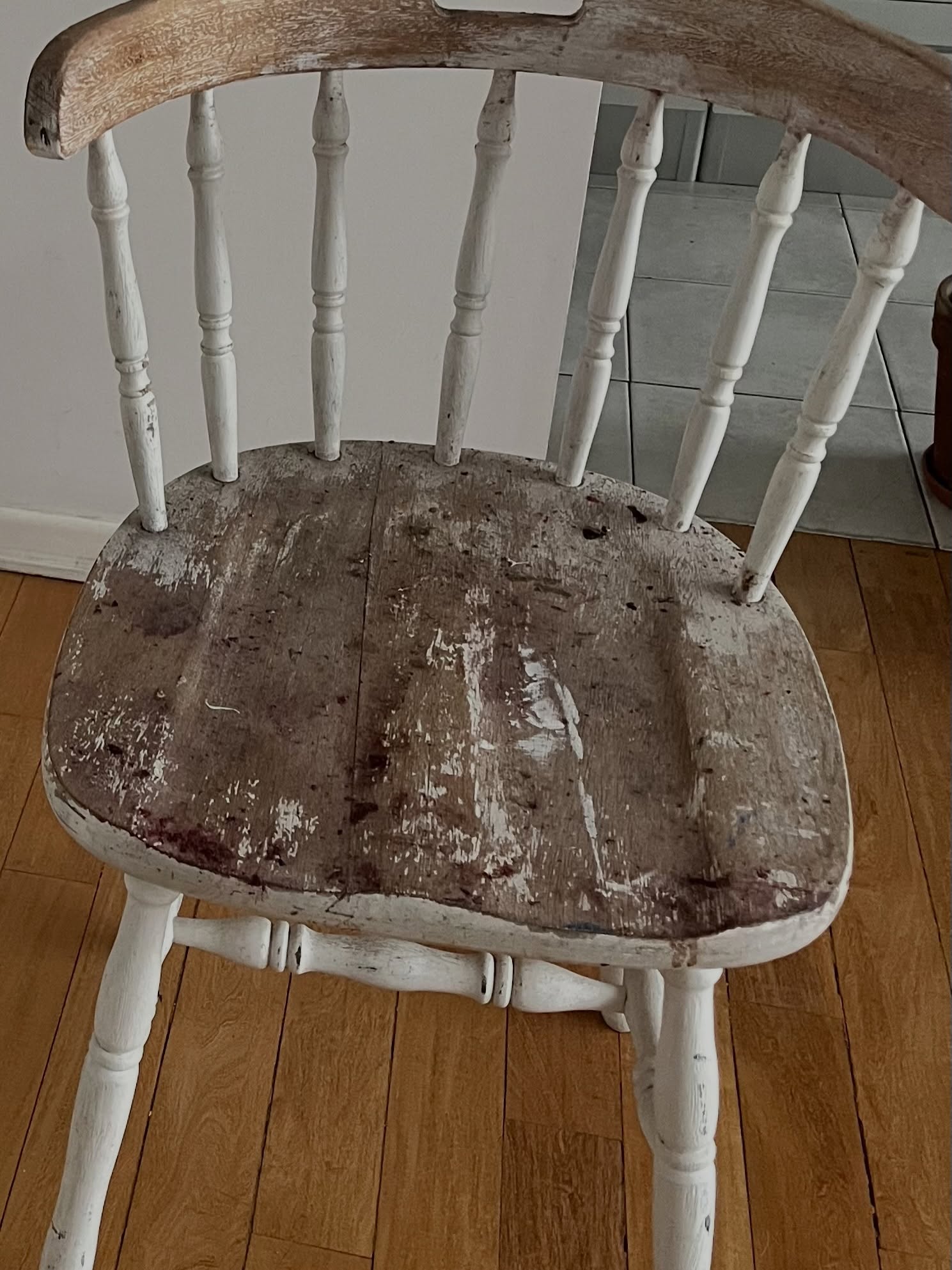 Silla antigua con pintura blanca descascarada y asiento de madera desgastado, vista desde arriba, antes de restaurar
